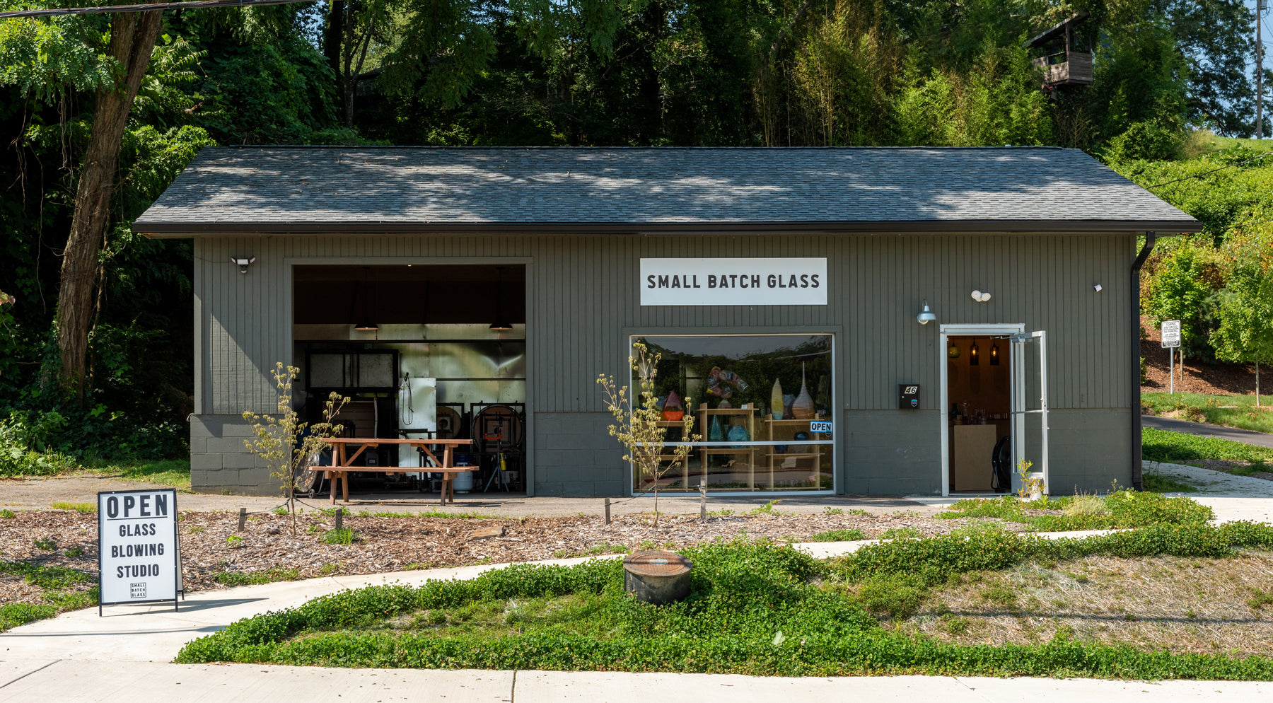 The facade of Small Batch Glass from the street. A gallery door sits open and a garage door leads into the hotshop. Image by Loam