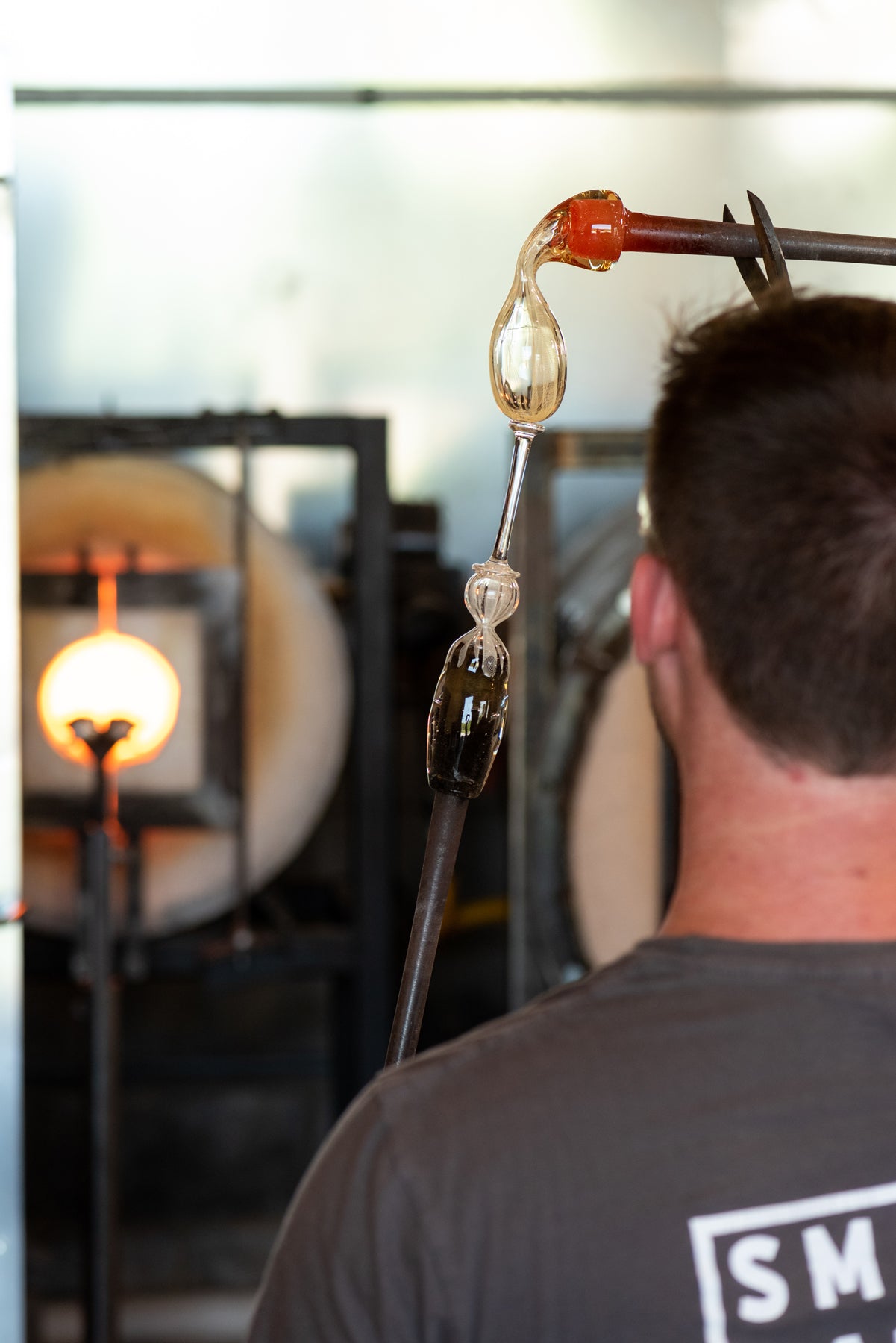 A process shot of a molten piece of inflated glass being added onto a thin rod of clear glass. Image by Loam 