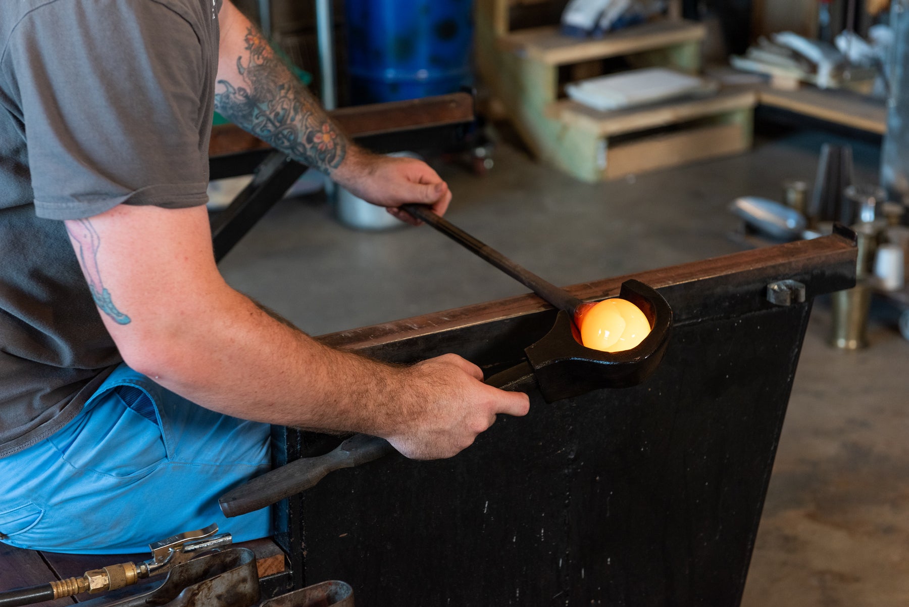 Asher Holman, owner and gaffer at small batch glass, is using a block to shape molten glass. Image by Loam