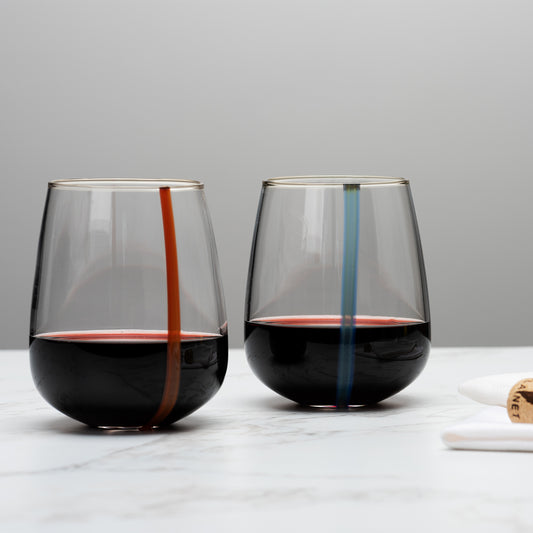 two stemless wineglasses with a stipe of color on each hold a deep red wine. Image by Loam